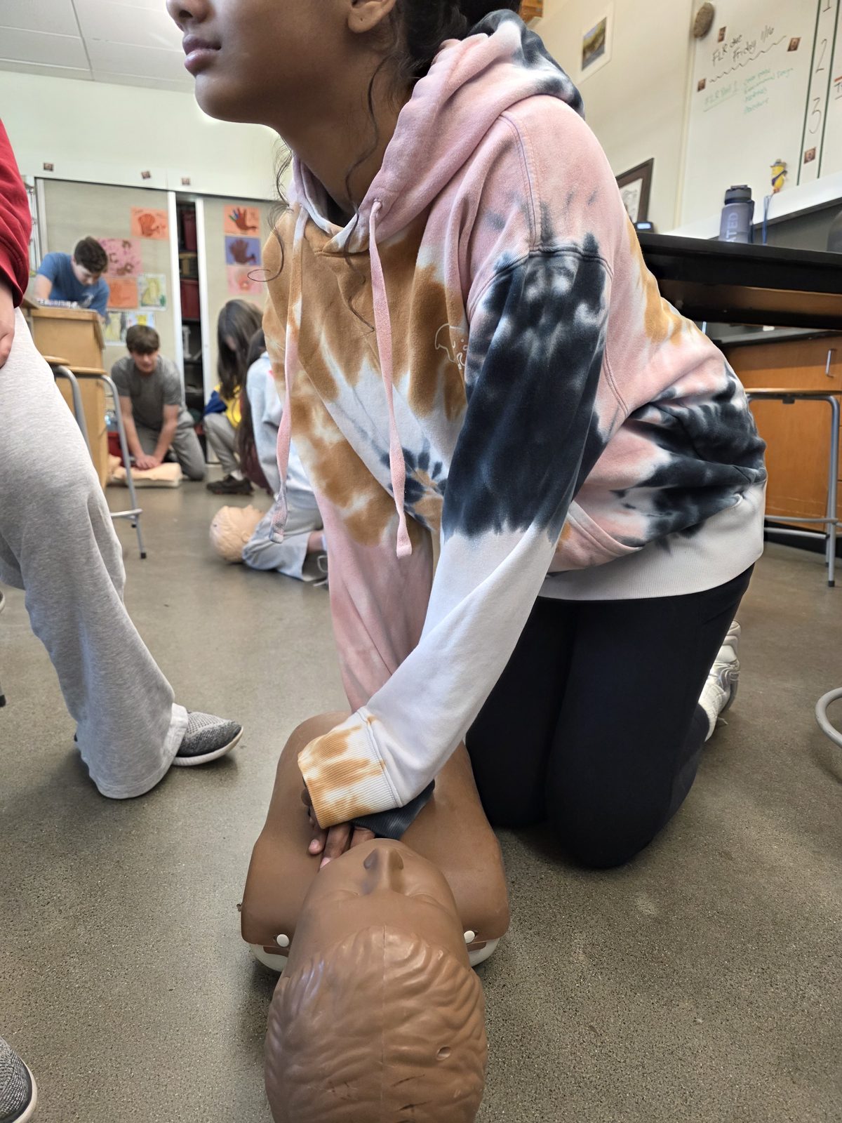 A student practicing CPR on a training manikin