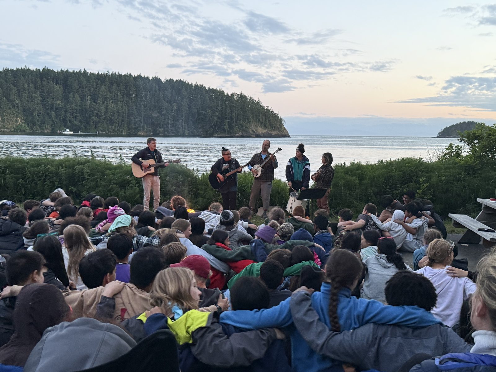 EAS teachers playing music together around the campfire at sunset during camp